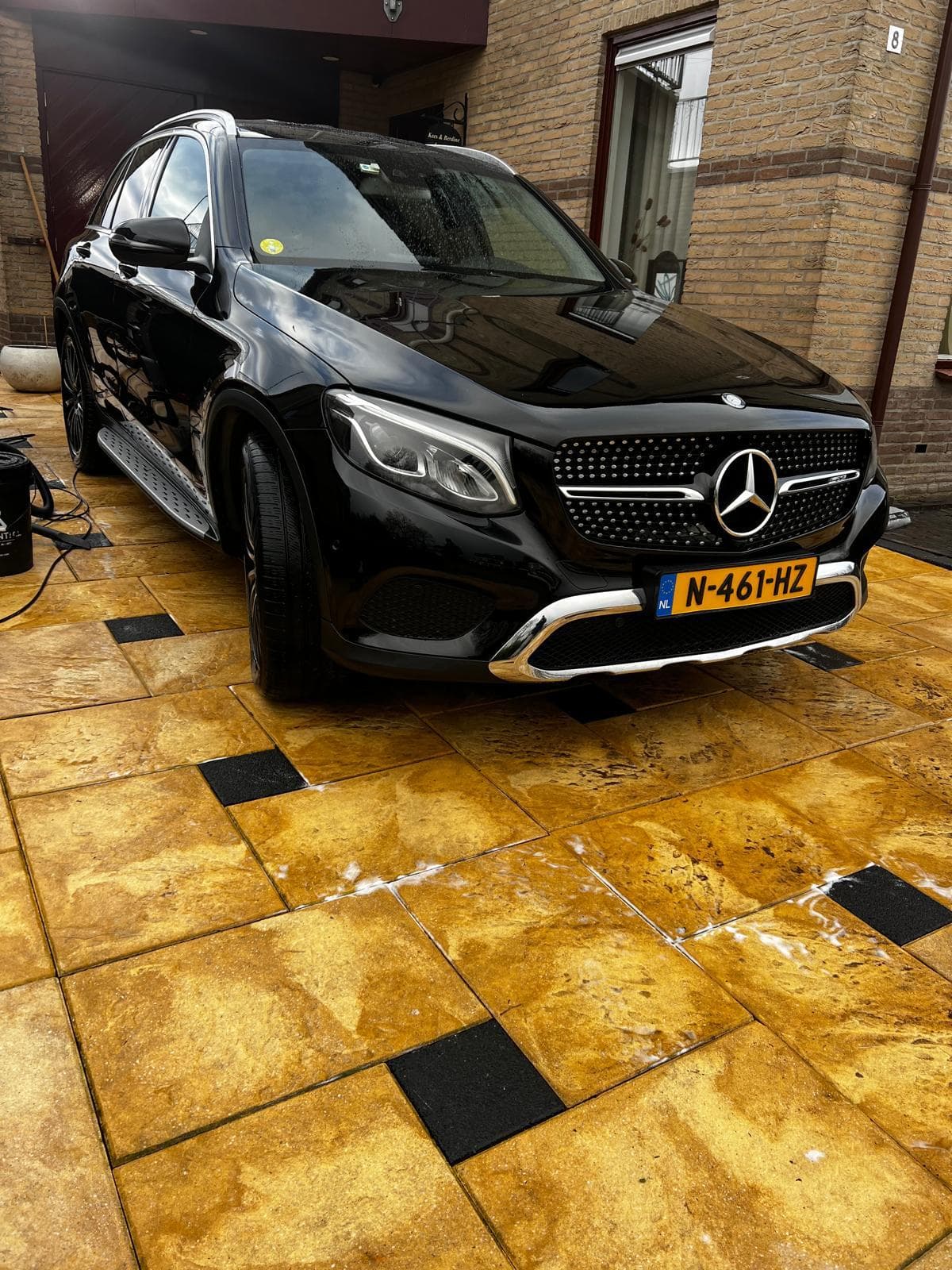 Zwarte Mercedes na reiniging op natte oprit.